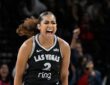 Las Vegas Aces guard Deja Kelly screams in celebration as fans cheer behind her.