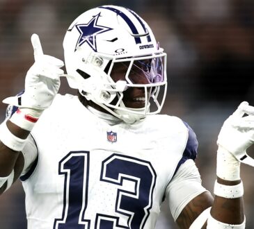 Dallas Cowboys linebacker DeMarvion Overshown smiles and gestures with both hands after a play.