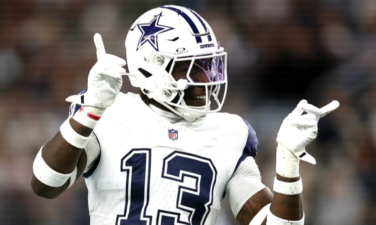 Dallas Cowboys linebacker DeMarvion Overshown smiles and gestures with both hands after a play.