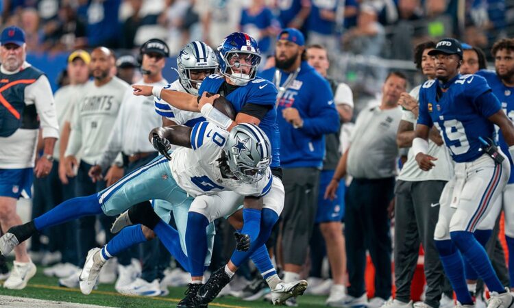 Dallas Cowboys linebacker DeMarvion Overshown drives New York Giants quarterback Jaxson Dart out of bounds near the sideline.