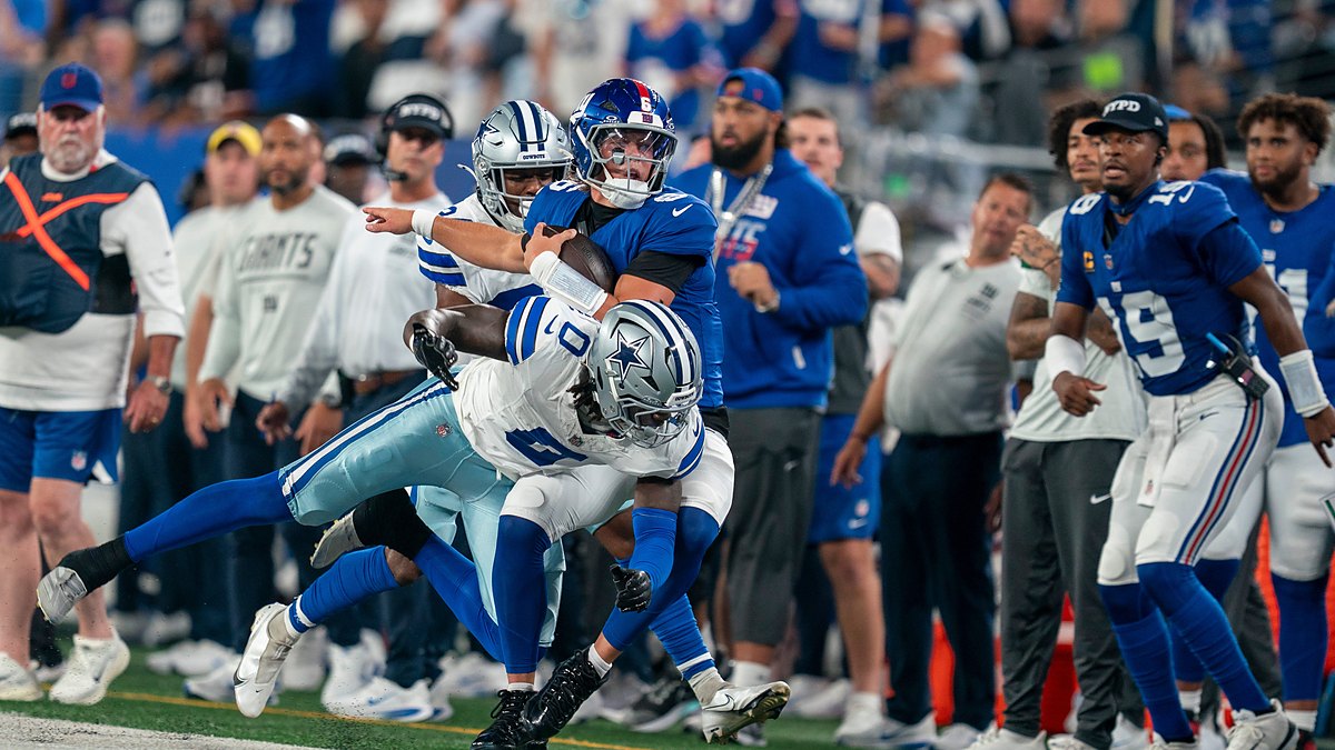 Dallas Cowboys linebacker DeMarvion Overshown drives New York Giants quarterback Jaxson Dart out of bounds near the sideline.