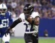 Ravens running back Derrick Henry tucks the ball and pulls away from a Colts defender on a touchdown run.