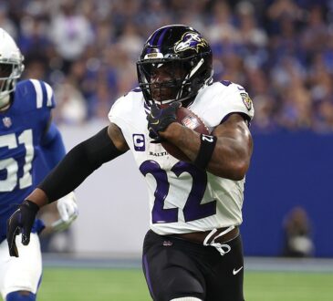 Ravens running back Derrick Henry tucks the ball and pulls away from a Colts defender on a touchdown run.