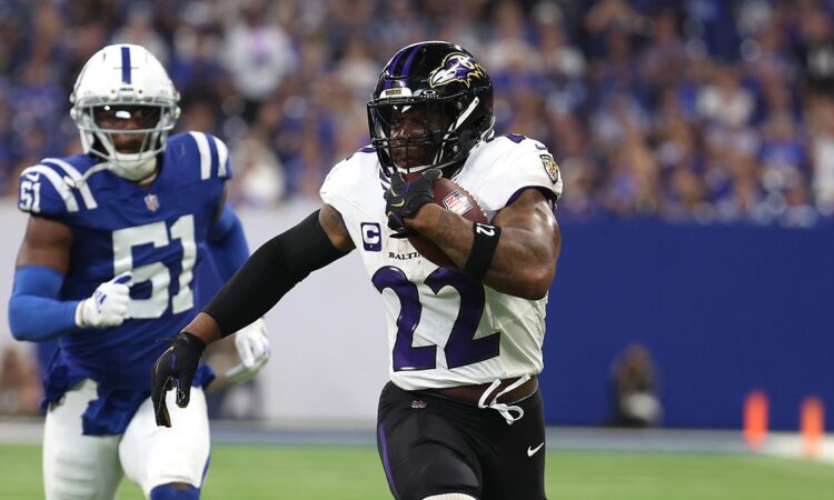 Ravens running back Derrick Henry tucks the ball and pulls away from a Colts defender on a touchdown run.