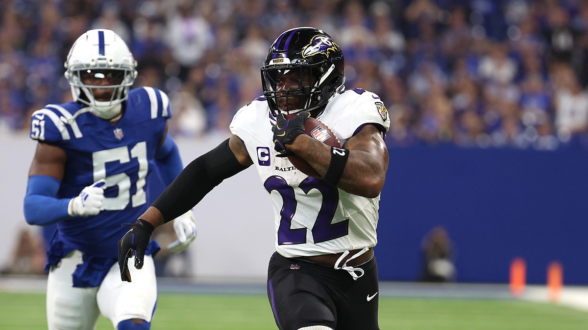 Ravens running back Derrick Henry tucks the ball and pulls away from a Colts defender on a touchdown run.