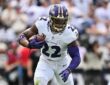 Baltimore Ravens running back Derrick Henry carries the ball upfield with a teammate blocking to his left.