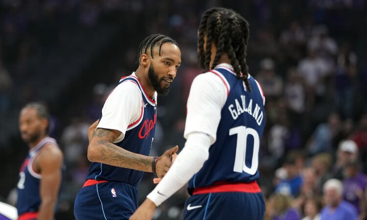 LA Clippers forward Derrick Jones Jr. reaches out to slap hands with teammate Darius Garland before tipoff.
