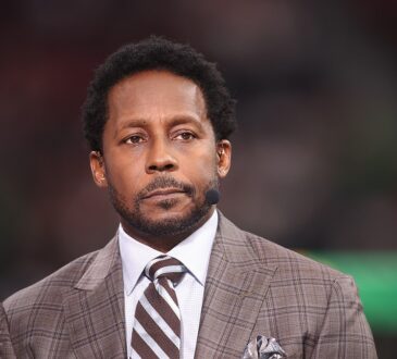 Alt Text: ESPN analyst Desmond Howard wears a headset microphone on the broadcast set before a College Football Playoff game.