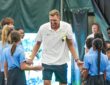 Former Dallas Mavericks forward Dirk Nowitzki smiles and slaps hands with children lining both sides of a tennis court.