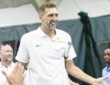 Former Dallas Mavericks forward Dirk Nowitzki smiles and high-fives a line of fans with a tennis racket tucked under his arm.