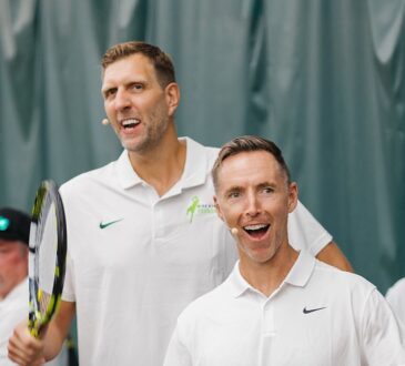 Former Dallas Mavericks forward Dirk Nowitzki smiles and high-fives an opponent across the net at a celebrity tennis match.