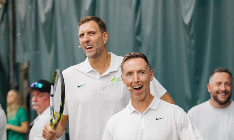 Former Dallas Mavericks forward Dirk Nowitzki smiles and high-fives an opponent across the net at a celebrity tennis match.