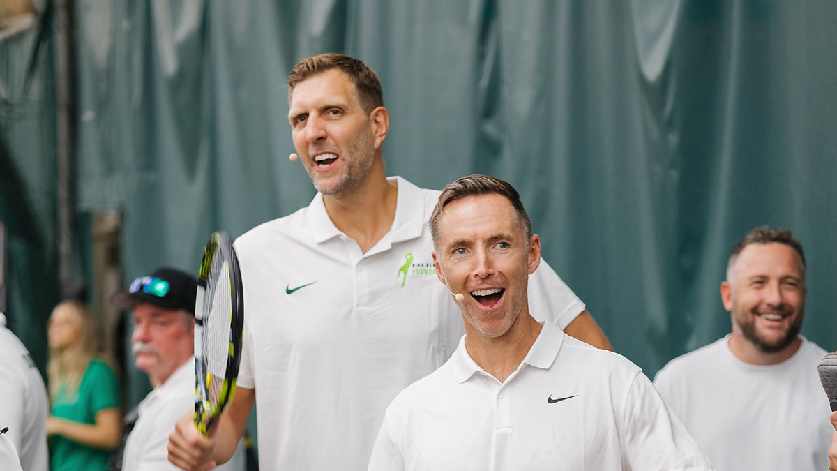 Former Dallas Mavericks forward Dirk Nowitzki smiles and high-fives an opponent across the net at a celebrity tennis match.