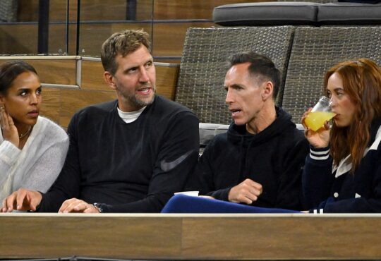 Former Dallas Mavericks teammates Dirk Nowitzki and Steve Nash talk while watching a tennis match from their seats.