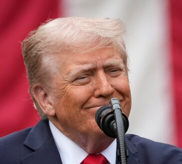 President Donald Trump speaks at a microphone in front of an American flag at a Pentagon memorial event.