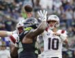 New England Patriots quarterback Drake Maye releases a pass as a Seattle defender raises a hand in front of him.