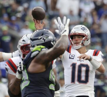 New England Patriots quarterback Drake Maye releases a pass as a Seattle defender raises a hand in front of him.