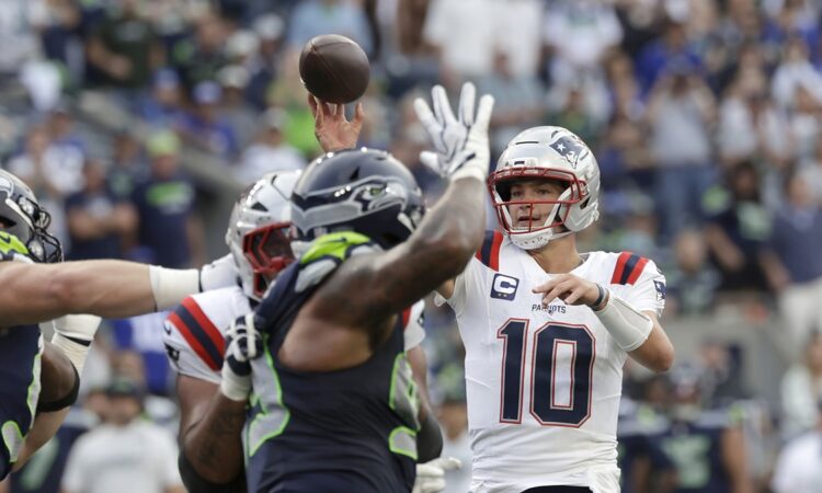 New England Patriots quarterback Drake Maye releases a pass as a Seattle defender raises a hand in front of him.