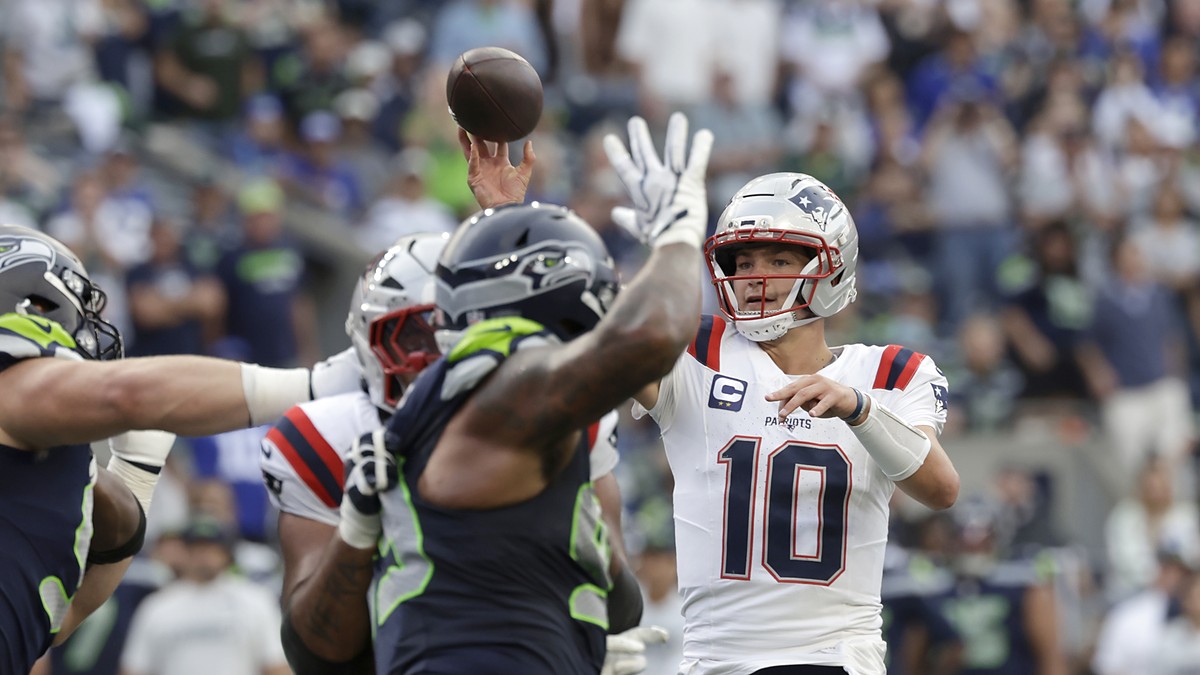 New England Patriots quarterback Drake Maye releases a pass as a Seattle defender raises a hand in front of him.