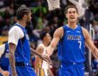 Dallas Mavericks forward Dwight Powell shouts as he slaps hands with forward Naji Marshall on the court.