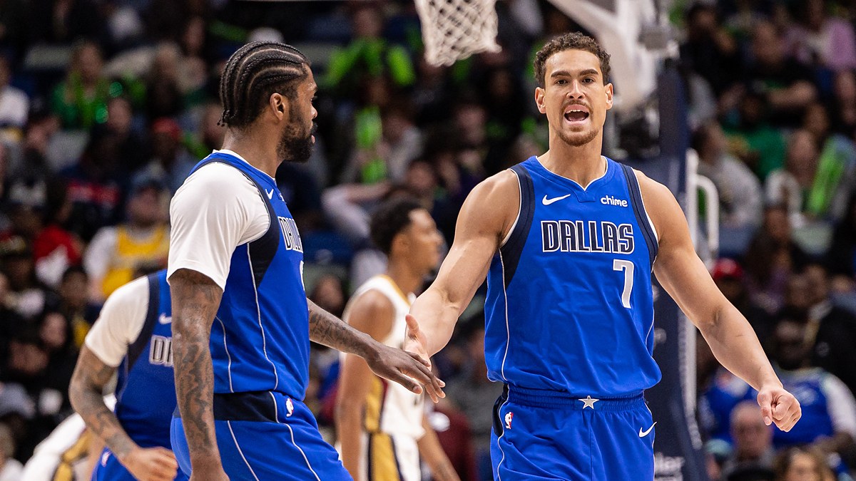 Dallas Mavericks forward Dwight Powell shouts as he slaps hands with forward Naji Marshall on the court.
