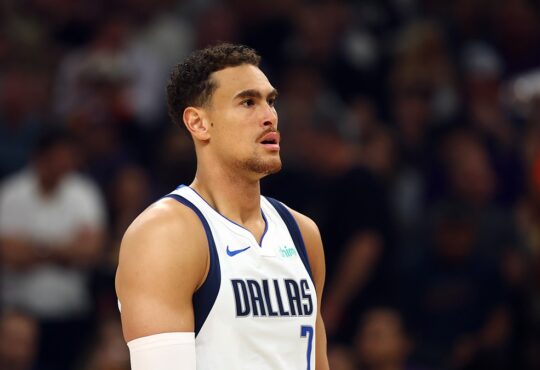 Dallas Mavericks forward Dwight Powell looks on during a game in his white Dallas jersey with a sleeve on his right arm.