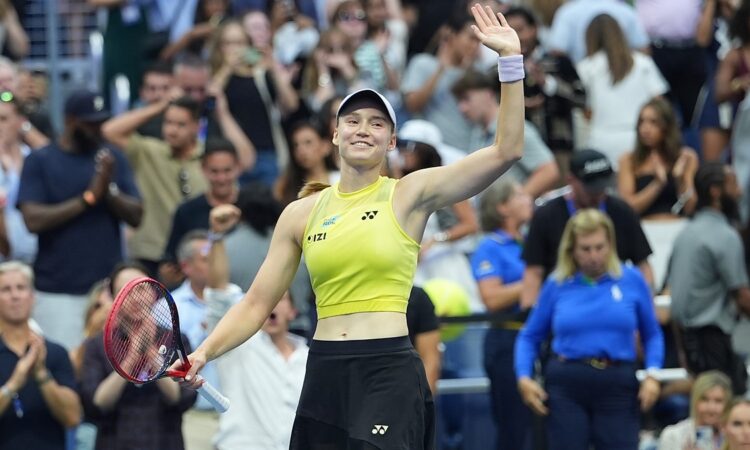 Elena Rybakina smiles and waves to the crowd with her racket in hand after a match.