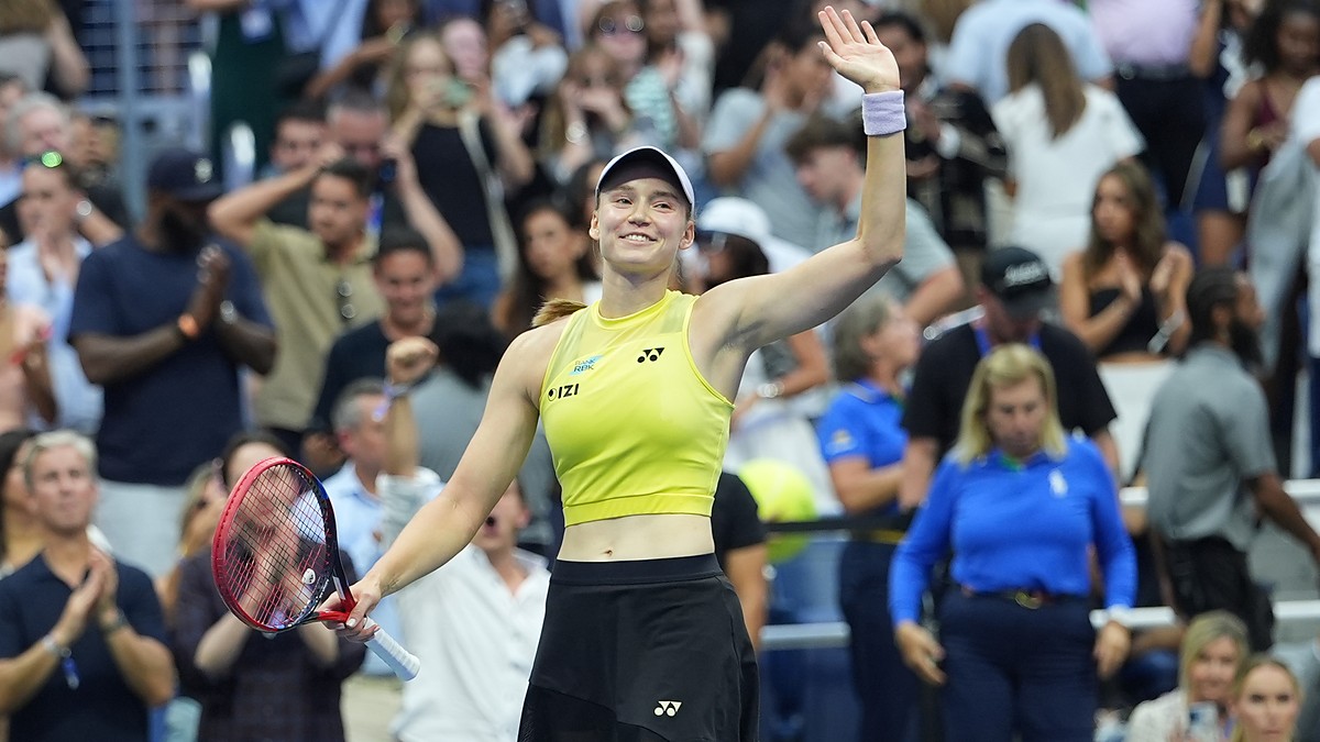 Elena Rybakina smiles and waves to the crowd with her racket in hand after a match.