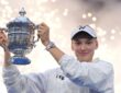 Elena Rybakina raises the U.S. Open trophy overhead as sparks fall behind her.