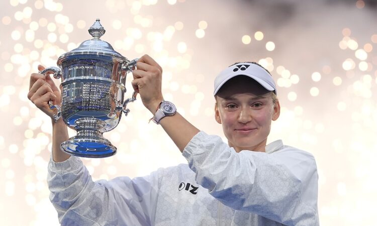 Elena Rybakina raises the U.S. Open trophy overhead as sparks fall behind her.