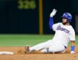 Texas Rangers catcher Elias Díaz slides into second base with his glove hand raised as dirt kicks up.