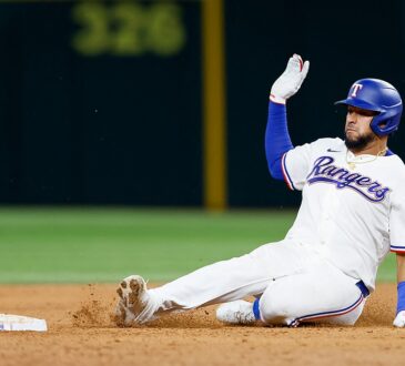 Texas Rangers catcher Elias Díaz slides into second base with his glove hand raised as dirt kicks up.