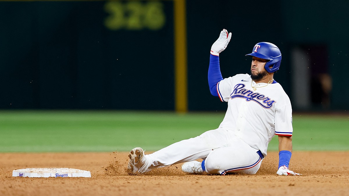 Texas Rangers catcher Elias Díaz slides into second base with his glove hand raised as dirt kicks up.