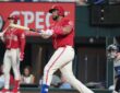 Texas Rangers catcher Elias Díaz, No. 35, follows through on a swing in a red alternate jersey.