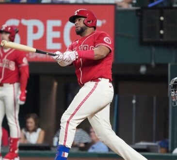 Texas Rangers catcher Elias Díaz, No. 35, follows through on a swing in a red alternate jersey.