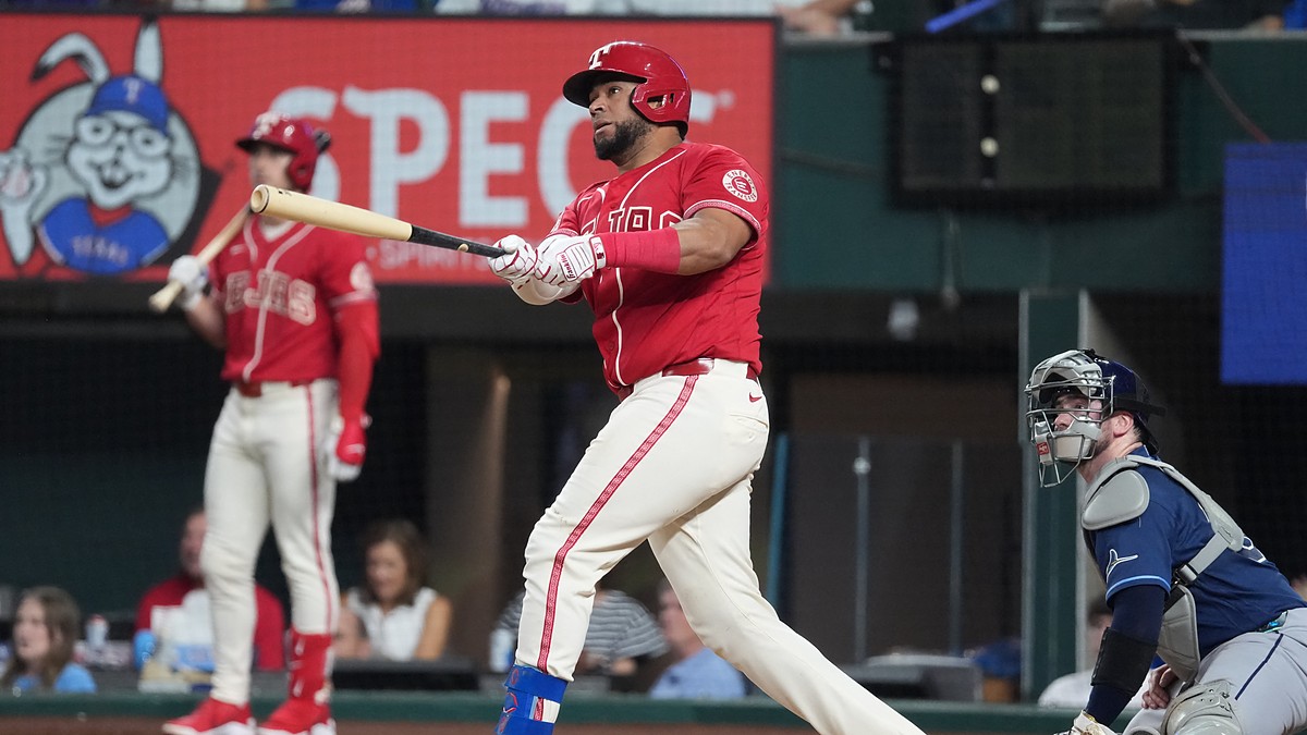 Texas Rangers catcher Elias Díaz, No. 35, follows through on a swing in a red alternate jersey.