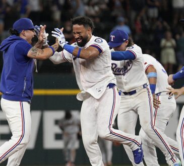 Texas Rangers players swarm Ezequiel Duran on the infield after his game-winning hit.