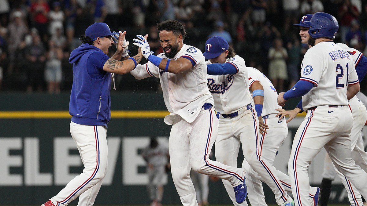 Texas Rangers players swarm Ezequiel Duran on the infield after his game-winning hit.
