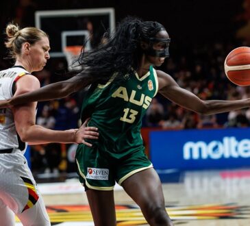 Australia center Ezi Magbegor, wearing a black face mask, reaches for the ball as Belgium’s Emma Meesseman defends.