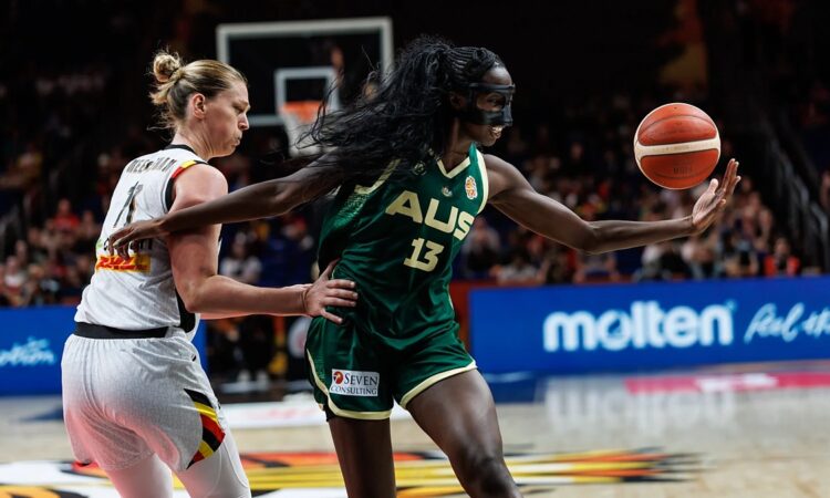 Australia center Ezi Magbegor, wearing a black face mask, reaches for the ball as Belgium’s Emma Meesseman defends.
