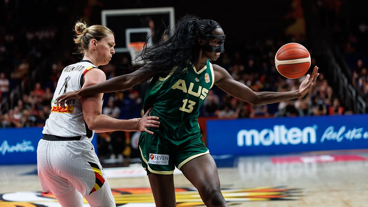 Australia center Ezi Magbegor, wearing a black face mask, reaches for the ball as Belgium’s Emma Meesseman defends.
