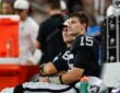 Las Vegas Raiders quarterback Fernando Mendoza sits on the bench beside Kirk Cousins during a preseason game.