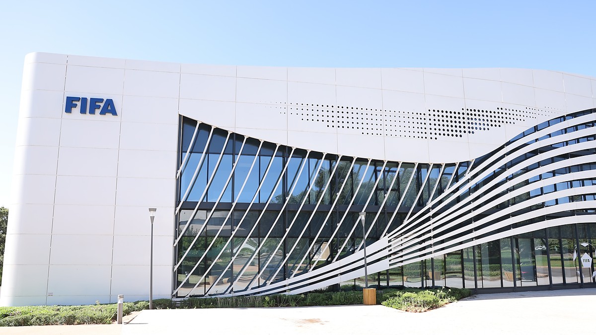 The blue FIFA wordmark mounted on the white facade of a curved glass FIFA office building.