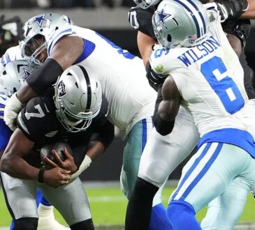 Las Vegas Raiders quarterback Geno Smith, No. 7, is wrapped up by two Dallas Cowboys defensive tackles.