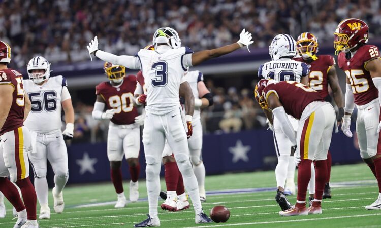 Dallas Cowboys wide receiver George Pickens spreads his arms wide and tilts his head back among Commanders defenders.