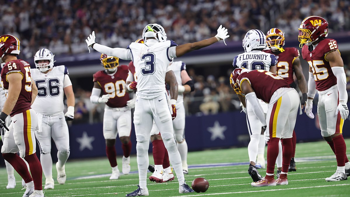 Dallas Cowboys wide receiver George Pickens spreads his arms wide and tilts his head back among Commanders defenders.