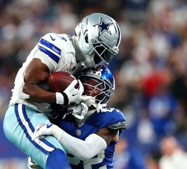 Cowboys wide receiver George Pickens secures the ball as Giants cornerback Dru Phillips wraps him up.