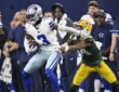 Dallas Cowboys wide receiver George Pickens holds the ball as Packers cornerback Carrington Valentine grabs him.