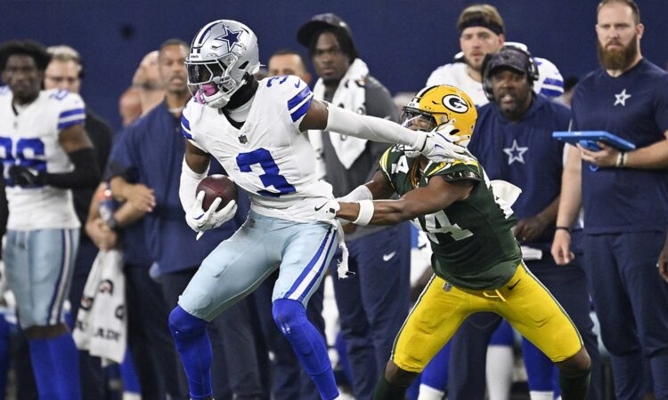 Dallas Cowboys wide receiver George Pickens holds the ball as Packers cornerback Carrington Valentine grabs him.