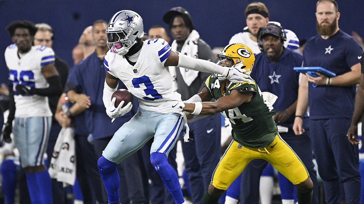 Dallas Cowboys wide receiver George Pickens holds the ball as Packers cornerback Carrington Valentine grabs him.